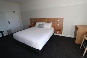 1 dormitorio con 1 cama blanca grande y cabecero de madera en Mortdale Hotel en Mortdale