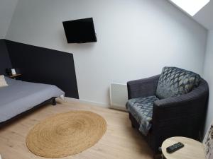 a room with a couch and a chair and a television at Maison entre Dinan et Dinard in Pleslin-Trigavou
