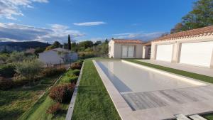 a swimming pool in a yard next to a house at La Tiny de Louis, au milieu des oliviers, avec jolie piscine in Draguignan