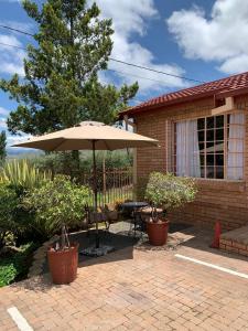 un patio con mesa y sombrilla en Clarens Eddies Guest house en Clarens