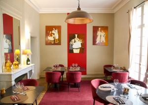 un restaurante con mesas y sillas y una pared roja en A Propos - Chambres d'Hôtes, en Orange