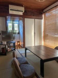 Una sala de estar con una mesa, una silla y un televisor. en 海と山と川、田園に囲まれた静かな古民家一棟貸し, en Miyazaki