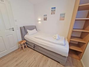 uma pequena cama num pequeno quarto com um banco em Wilde Brise 2 Topniveau in Toplage mit Sauna em Norden