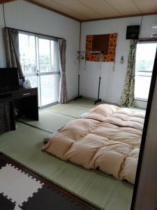 1 dormitorio con 2 camas, escritorio y ventana en ゲストハウスジェイズ, en Amagi