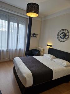 een slaapkamer met een bed met een stoel en een lamp bij Hotel Le Splendid in Troyes