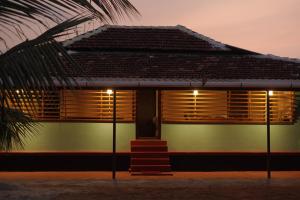 a house with wooden shuttered windows and a palm tree at Greene Villa in Palakkad