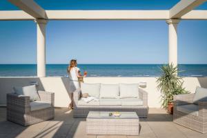 una donna in piedi su un patio con vista sulla spiaggia di Hotel Riviera a Milano Marittima