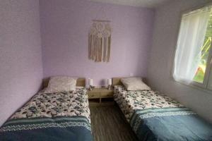 two beds in a bedroom with purple walls at Appartement au bord du lac avec terrasse in La Tour-dʼAuvergne