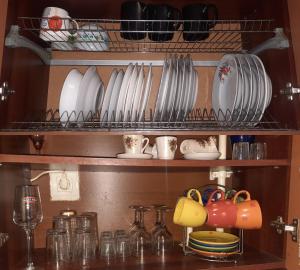 a shelf with plates and cups and dishes on it at Затишна, домашня 43м в тихому зеленому місці Поруч Центральний парк Університет in Irpin'