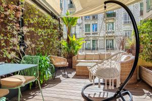 a patio with a table and chairs on a deck at Hôtel de France, un hôtel AMMI in Nice