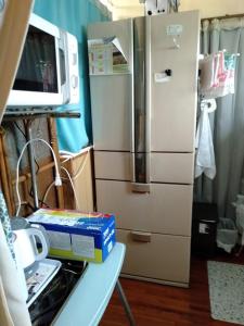 eine Küche mit einem Kühlschrank und Kisten auf dem Tisch in der Unterkunft ゲストハウスジェイズ in Amagi