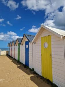 a row of beach huts lined up on the beach at Appartement avec jardin et accès mer in Grandcamp-Maisy
