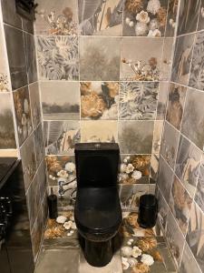 a bathroom with a black toilet in a tiled wall at Tüyap Fair Elit Home in Istanbul