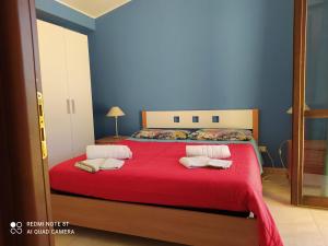 a bedroom with a red bed with two pillows on it at Villa Antonella in Noto Marina