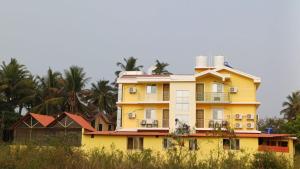 a yellow house with palm trees in the background at GLEN RESIDENCY in Dramapur