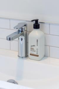 Relaxing City Hideaway - 2 Bed in Christchurch CBD في كرايستشيرش: زجاجة غسول الفم وموزع الصابون على حوض الحمام +50 صورة