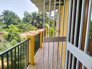 Elle dispose d'un balcon avec vue sur une maison dotée de murs jaunes et d'arbres. dans l'établissement Moradia Turistica MJ ROOMS CITY, à São Tomé
