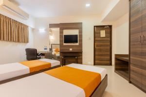 a hotel room with two beds and a desk and a tv at Hotel Prime in Ahmedabad