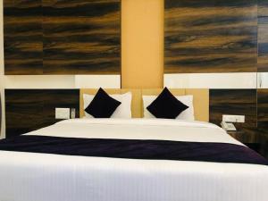 a bedroom with a large white bed with black pillows at Hotel Milan Bijapur in Bijāpur