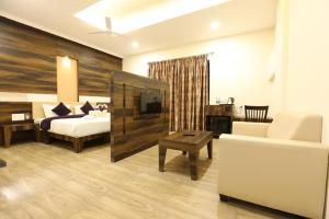 a hotel room with a bed and a living room at Hotel Milan Bijapur in Bijāpur