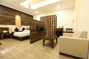 a hotel room with a bed and a living room at Hotel Milan Bijapur in Bijāpur