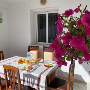 een eettafel met bloemen en eten erop bij Ziu Guest House in Berat