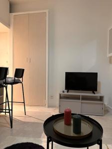 ein Wohnzimmer mit einem TV und einem Tisch in der Unterkunft Studio charmant proche Paris in Issy-les-Moulineaux