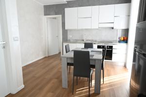 a kitchen with a table and chairs and white cabinets at Perla Marina 2 Acitrezza in Acitrezza