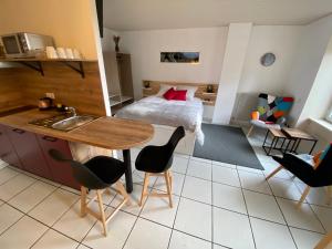 a room with a bed and a kitchen with a table and chairs at L'Oustal Des Dômes in Orcines