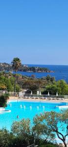 a large swimming pool with the ocean in the background at Perle d'or vue mer in Saint-Raphaël