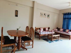 ein Wohnzimmer mit einem Tisch, Stühlen und einem Sofa in der Unterkunft Cozy 2BHK flat @ Vijaynagar 2nd stage Mysore in Mysore