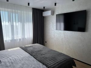 1 dormitorio con 1 cama y TV de pantalla plana en Комфортний люкс, en Khmelʼnytsʼkyy