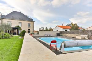 uma piscina com uma cadeira vermelha ao lado de uma casa em Maison Marie Barrault em Les Herbiers