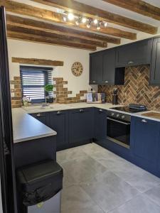 a kitchen with navy blue cabinets and a counter at The Barn in Shirland