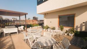 un patio con mesas blancas y sillas en el balcón en Blessings Hotel en Amritsar