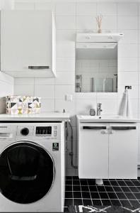 a white kitchen with a washing machine and a sink at DreamHouse in Sollentuna