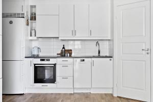 a white kitchen with white appliances and a white door at DreamHouse in Sollentuna