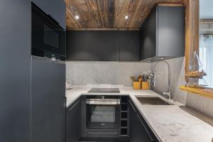 une cuisine avec un évier et une cuisinière four supérieur dans l'établissement Appartement Sifflote - LES CHALETS COVAREL, à La Daille
