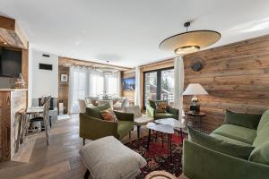 a living room with green furniture and wooden walls at Appartement Sifflote - LES CHALETS COVAREL in La Daille