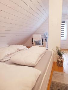 a bed with white sheets and a chair in a room at Ferienhaus Svensson Altheide in Altheide