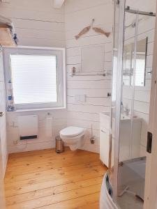 a white bathroom with a toilet and a window at Ferienhaus Svensson Altheide in Altheide +18 photos