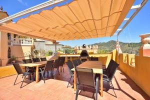 a patio with tables and chairs under a wooden umbrella at Villa rural en Málaga con piscina y vistas al mar in Málaga