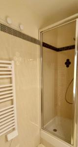 La salle de bains est pourvue d'une douche avec une porte en verre. dans l'établissement Studio DUNES de NALA avec balcon vue Dunes et latérale Mer pour 4 pers 100m plage wifi ménage compris, à Fort-Mahon-Plage