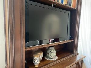 a wooden entertainment center with a television on a shelf at 5 stanze nella Villa dei Sogni in Madonna del Rio