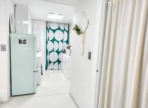 un couloir blanc avec une porte menant à une salle de bains. dans l'établissement Near Mangwon Market, 5mins to Hongdae Station by car, à Séoul