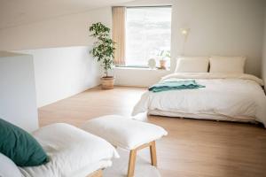 ein weißes Schlafzimmer mit einem Bett und einem Stuhl in der Unterkunft Jeju Green Stay Nuguhana in Jeju-do