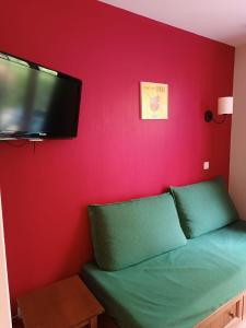 Habitación con sofá verde y TV de pantalla plana. en Petite maison dans Résidence, en Monflanquin