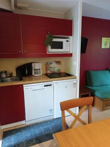 uma pequena cozinha com um micro-ondas branco e uma mesa em Petite maison dans Résidence em Monflanquin
