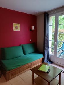 uma sala de estar com um sofá verde e uma mesa em Petite maison dans Résidence em Monflanquin