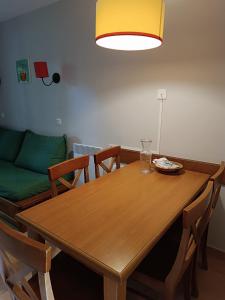 uma mesa de jantar em madeira com cadeiras e um sofá em Petite maison dans Résidence em Monflanquin